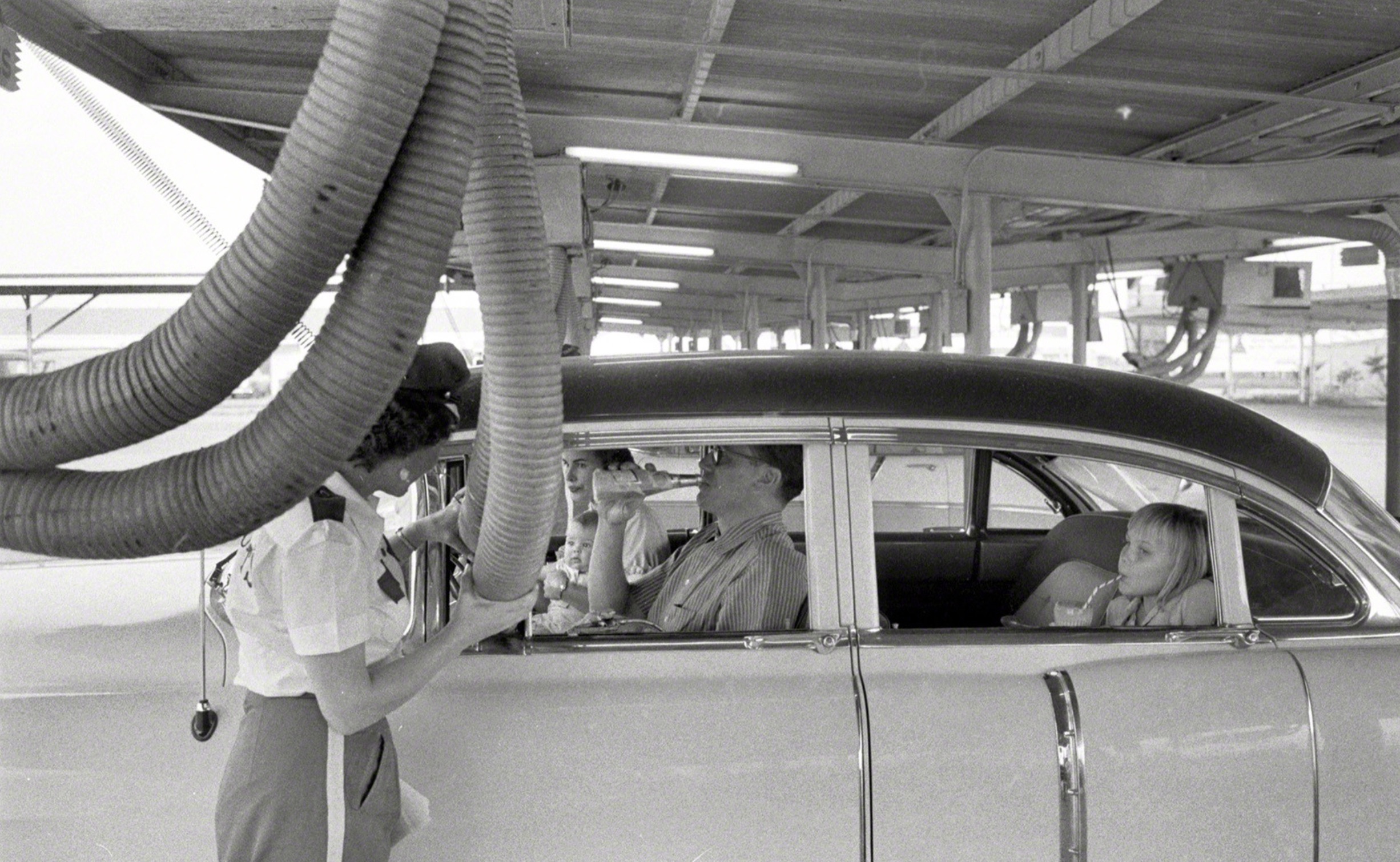 Getting cooled air piped into the car while enjoying a meal at a drive-in restaurant. Houston, Texas, 1957 
